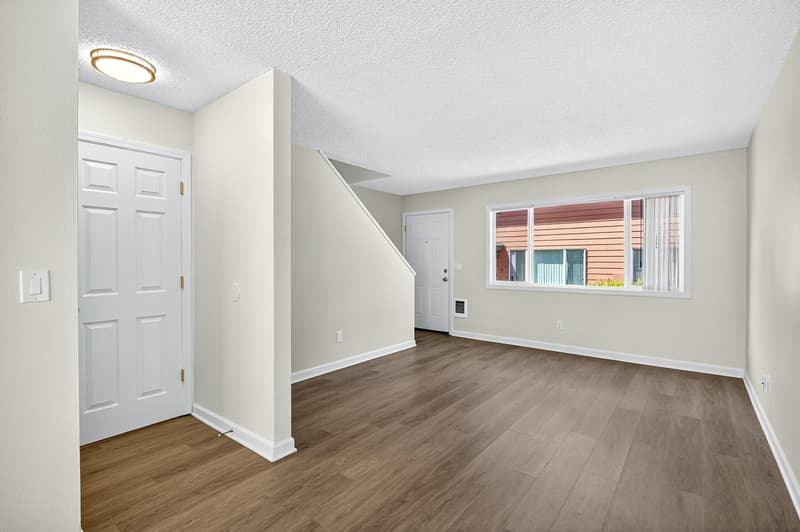 Bright living room with hardwood floors and large windows at Lincoln Court apartments in Fairview, Oregon